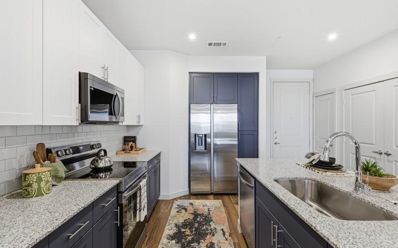 a kitchen with white and blue cabinets, kitchen island, stools, and wood floors
