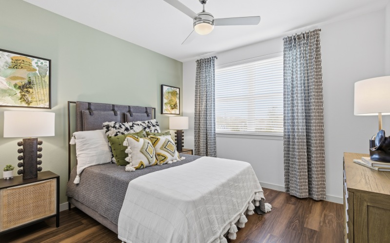bedroom with wood floors, window, bed, table, lamp, ceiling fan
