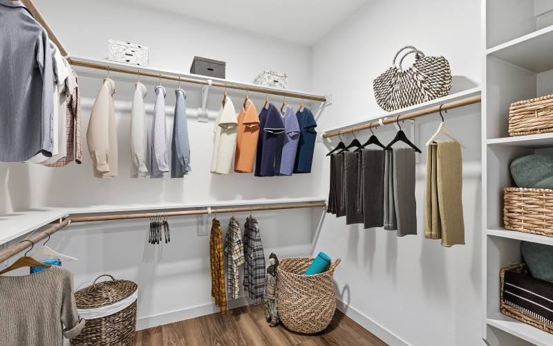 closet with clothes, shelving, and wood floors