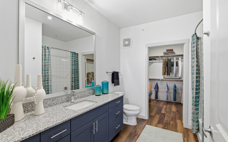 bathroom with blue cabinets, deep soaking bathtub and large mirror
