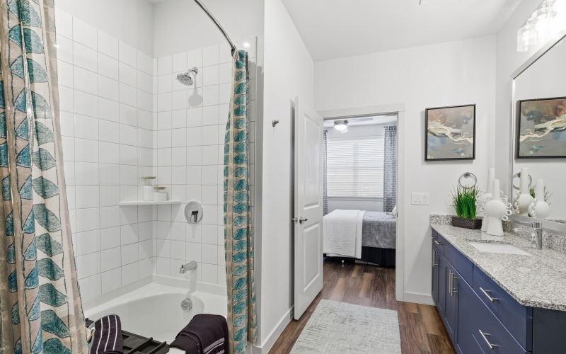 bathroom with blue cabinets, deep soaking bathtub and large mirror